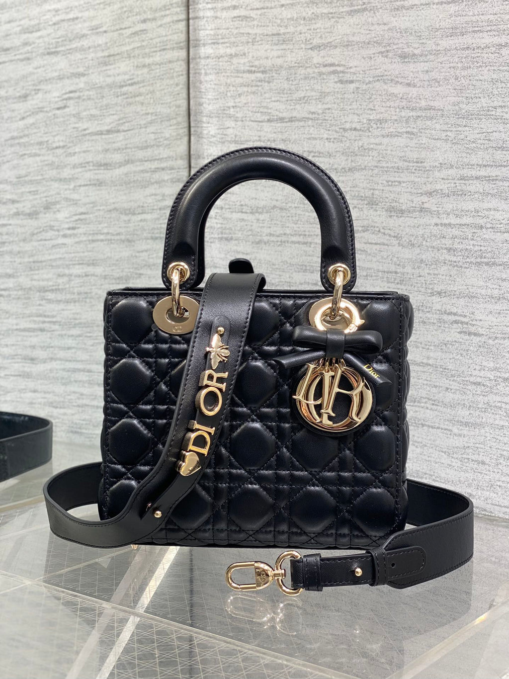 Black quilted mini handbag with top handle, bow accent, and gold-tone charms