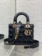 Black quilted mini handbag with top handle, bow accent, and gold-tone charms