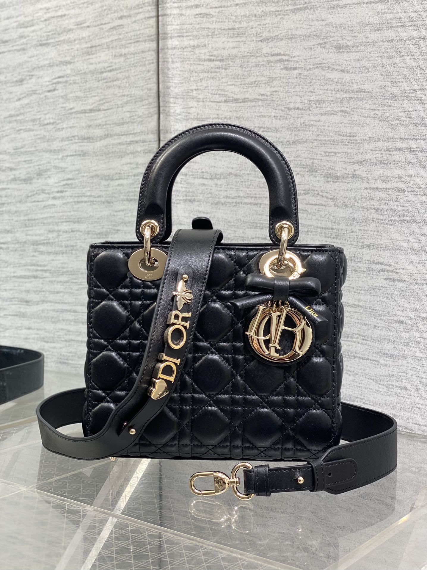 Black quilted mini handbag with top handle, bow accent, and gold-tone charms