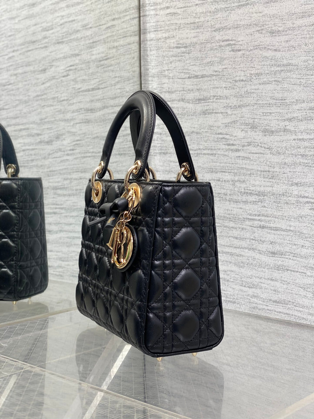 Black quilted mini handbag viewed from side with gold-tone charms on handle