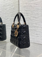 Black quilted mini handbag viewed from side with gold-tone charms on handle