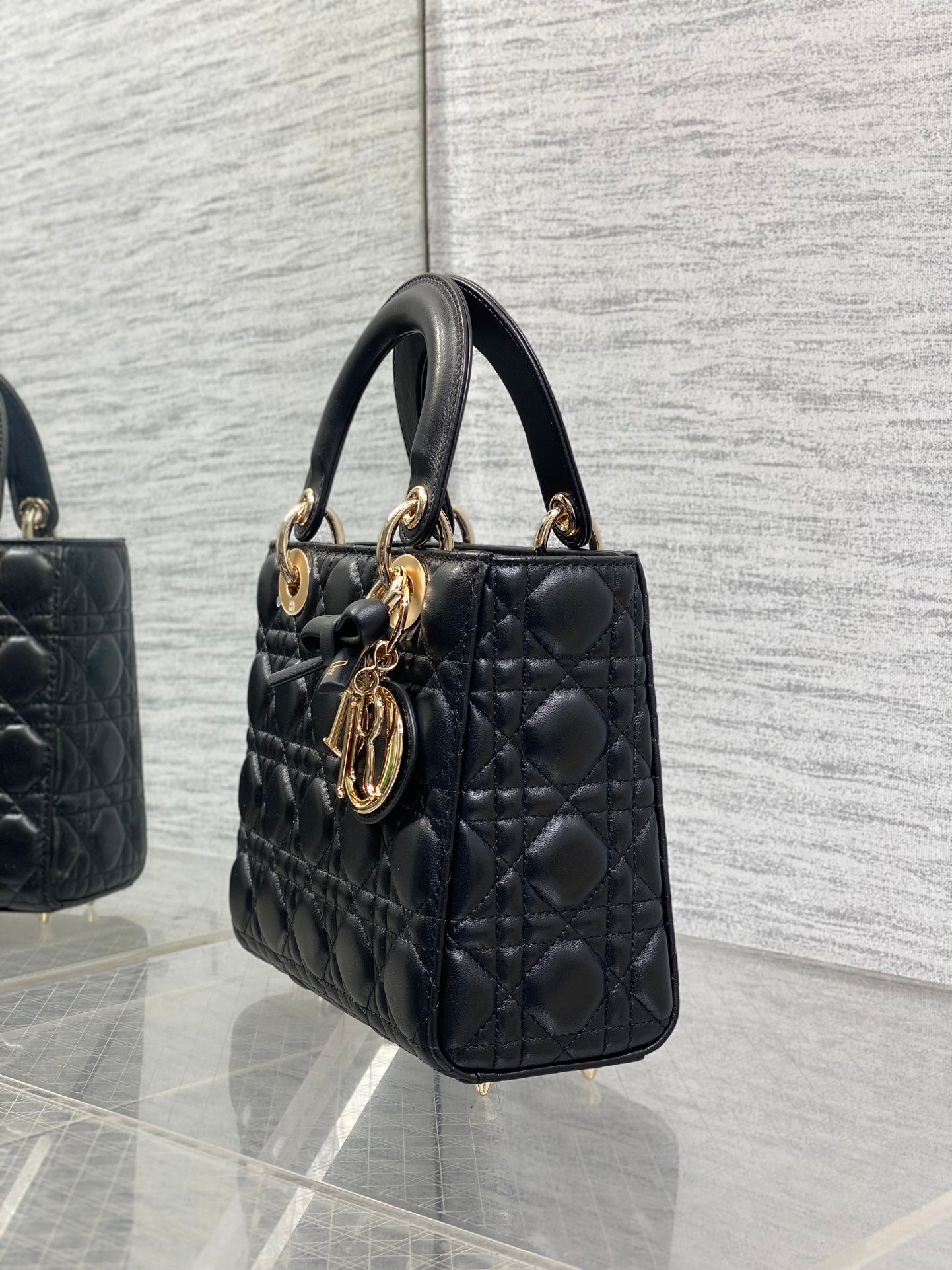 Black quilted mini handbag viewed from side with gold-tone charms on handle
