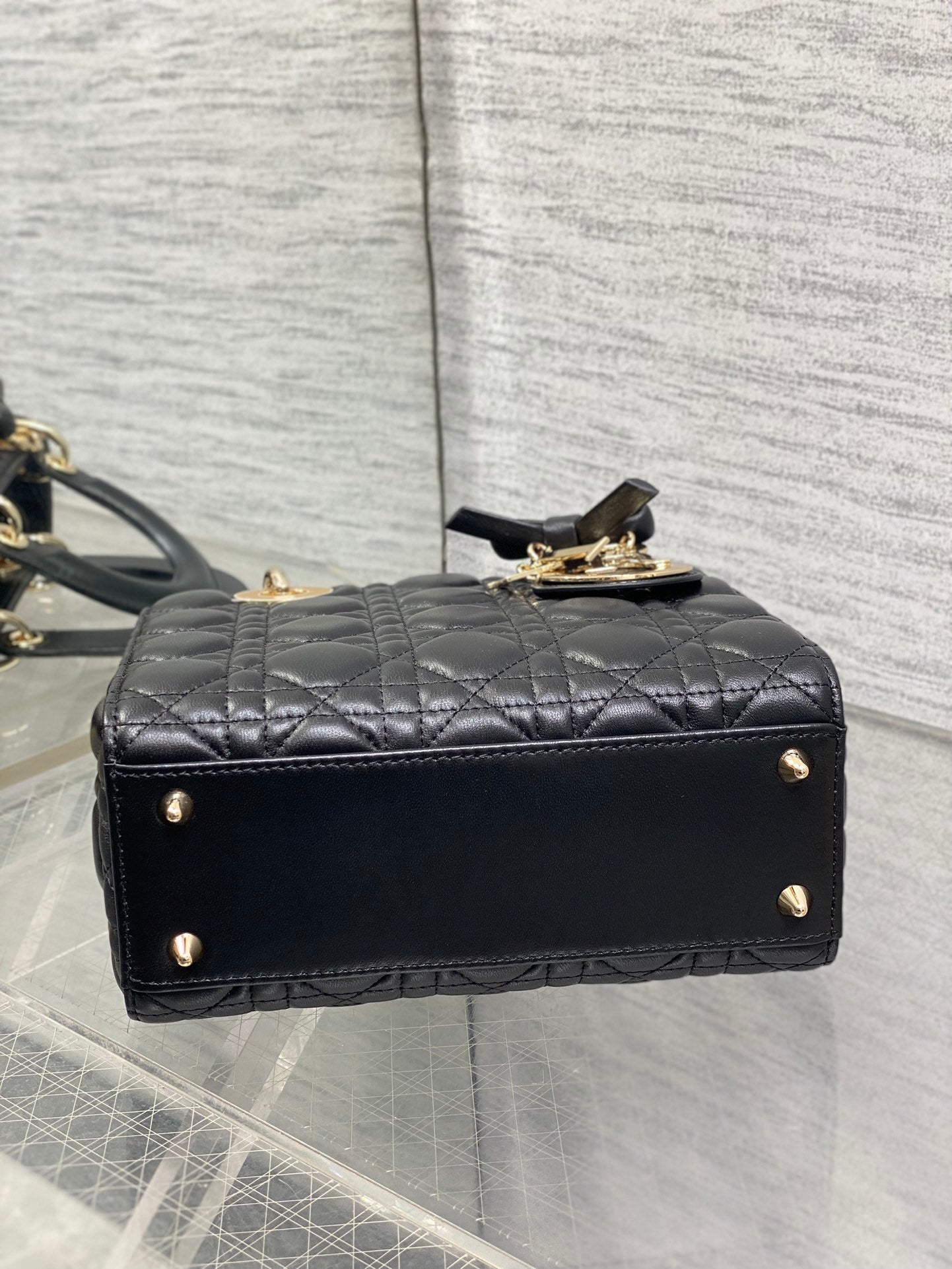 Black quilted mini handbag back view with small gold-tone feet and clasp