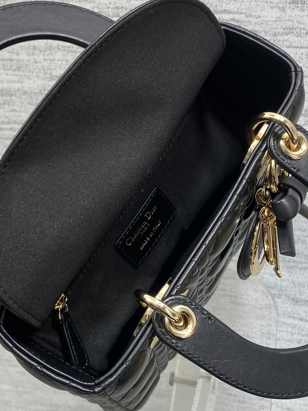 Black leather mini bag interior opening with gold-tone zipper and D-ring charm