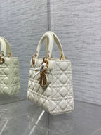 White quilted handbag with shoulder strap and central gold-tone charm