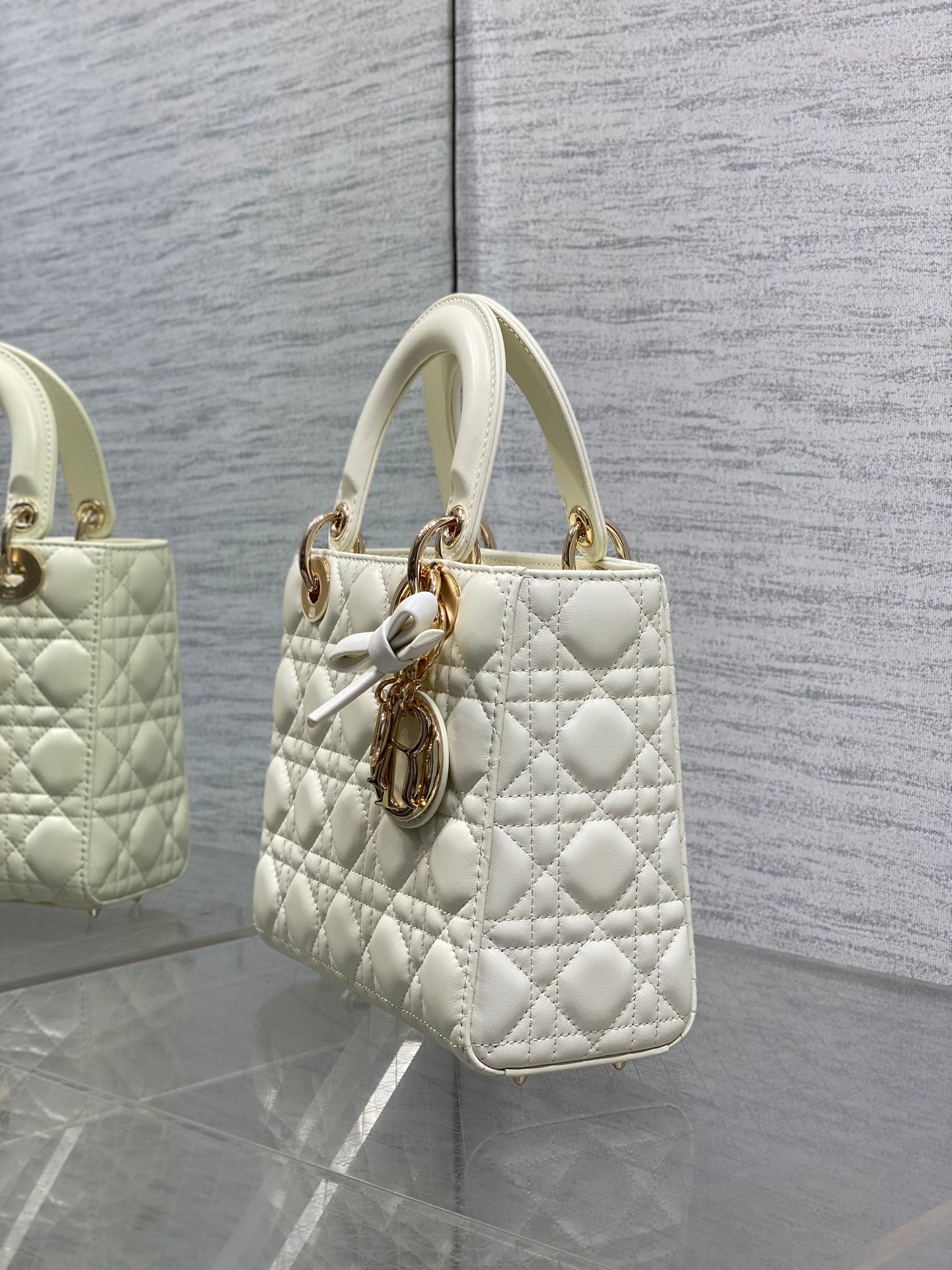 White quilted handbag with shoulder strap and central gold-tone charm