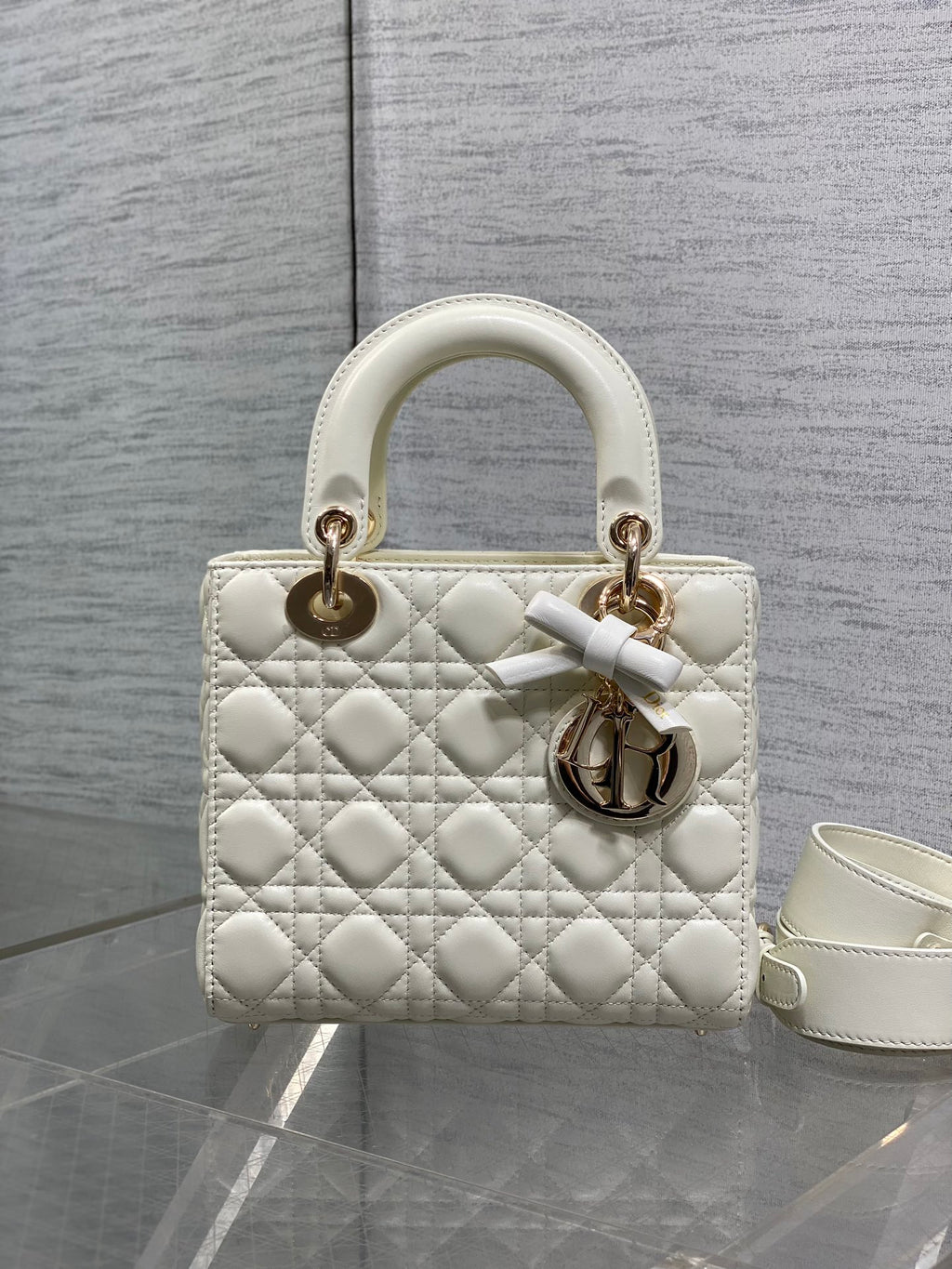 White quilted handbag with rounded handles and gold-tone charm detail