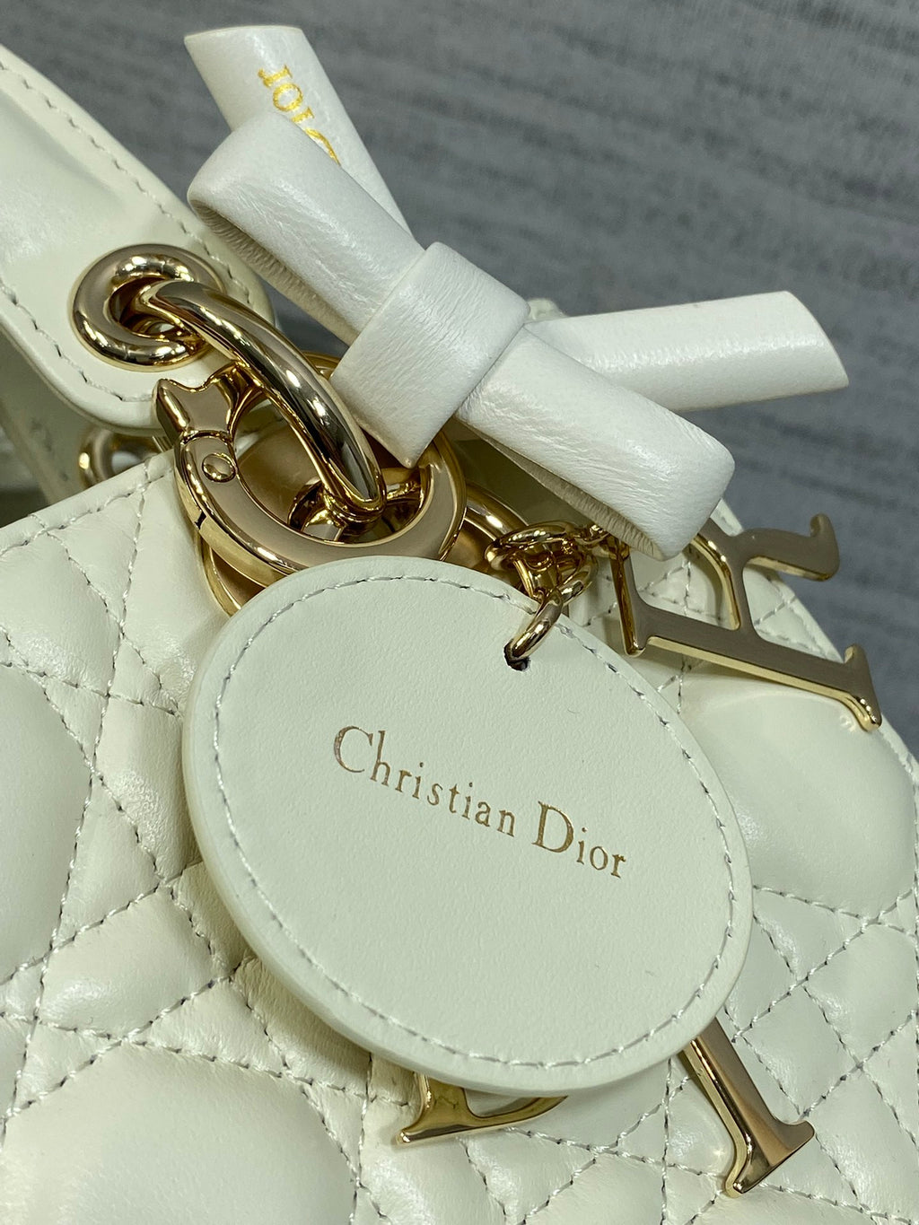 White leather handbag charm tag with Christian Dior name on round plate