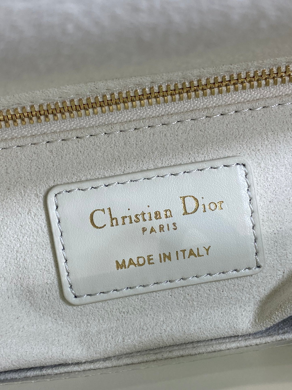 White leather bag label reading Christian Dior Paris, made in Italy