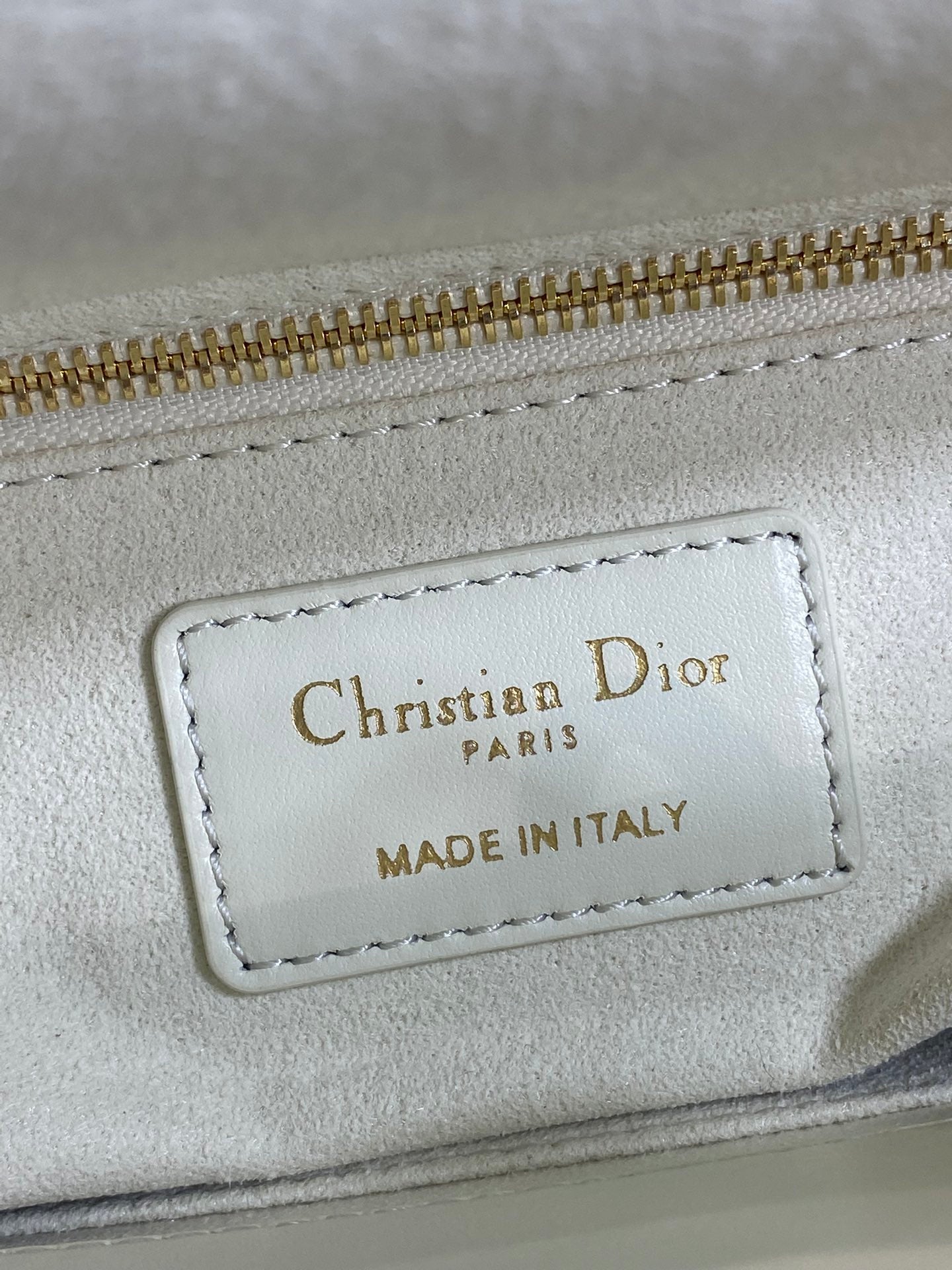 White leather bag label reading Christian Dior Paris, made in Italy