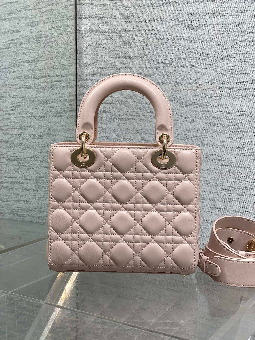 Light pink quilted mini handbag with rounded handles and adjustable crossbody strap