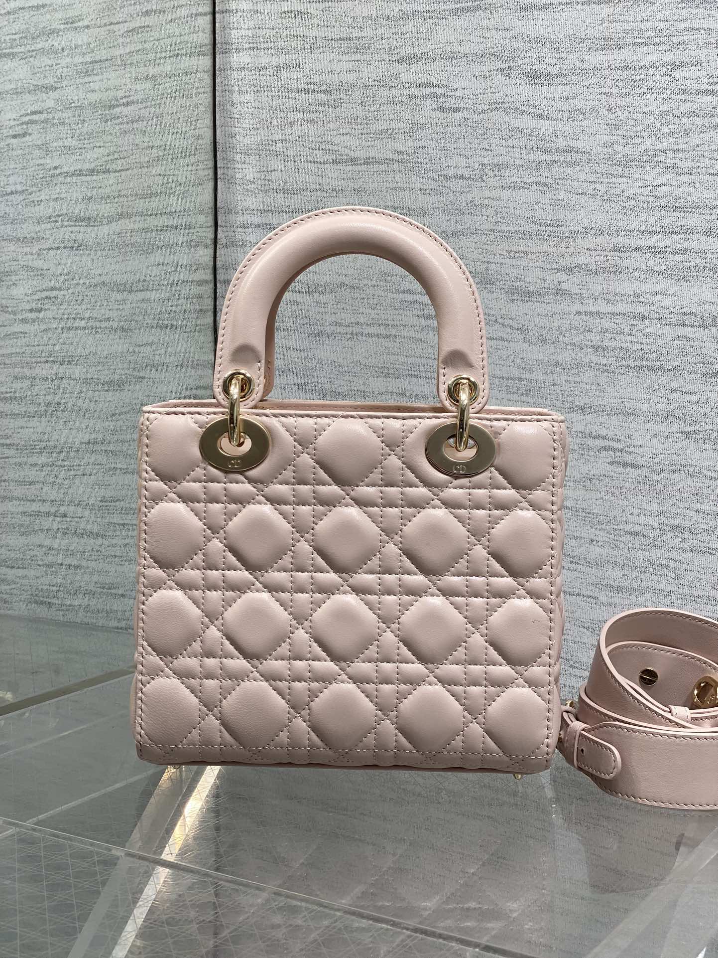 Light pink quilted mini handbag with rounded handles and adjustable crossbody strap