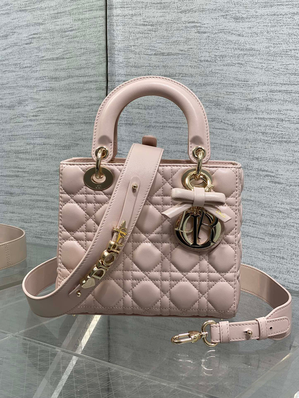 Light pink quilted mini handbag with top handles, bow detail, and shoulder strap