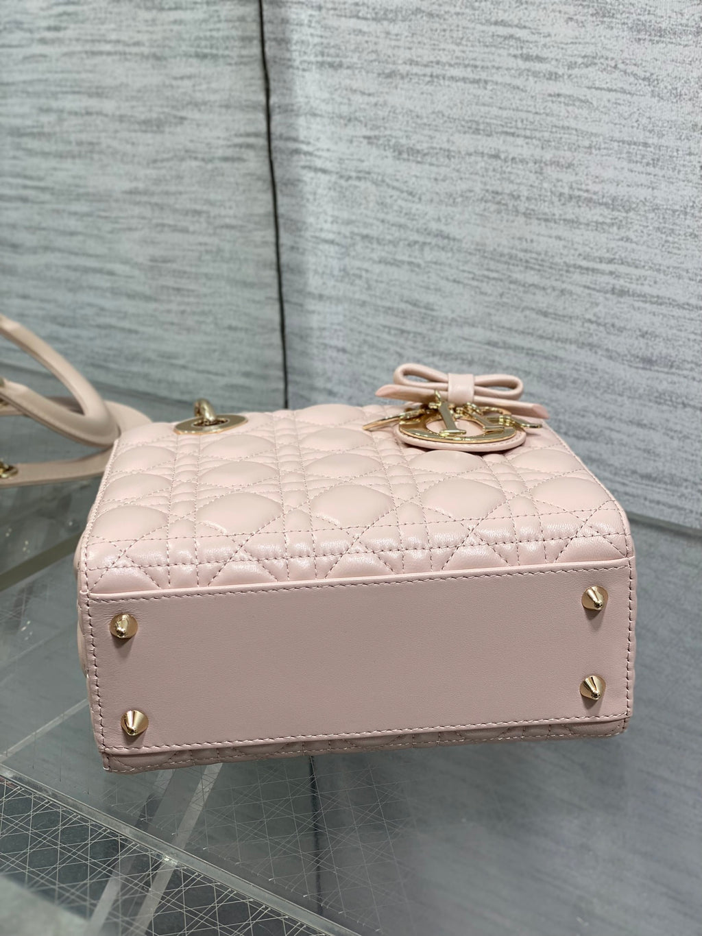 Light pink quilted handbag with top bow detail and gold-tone studs along the front