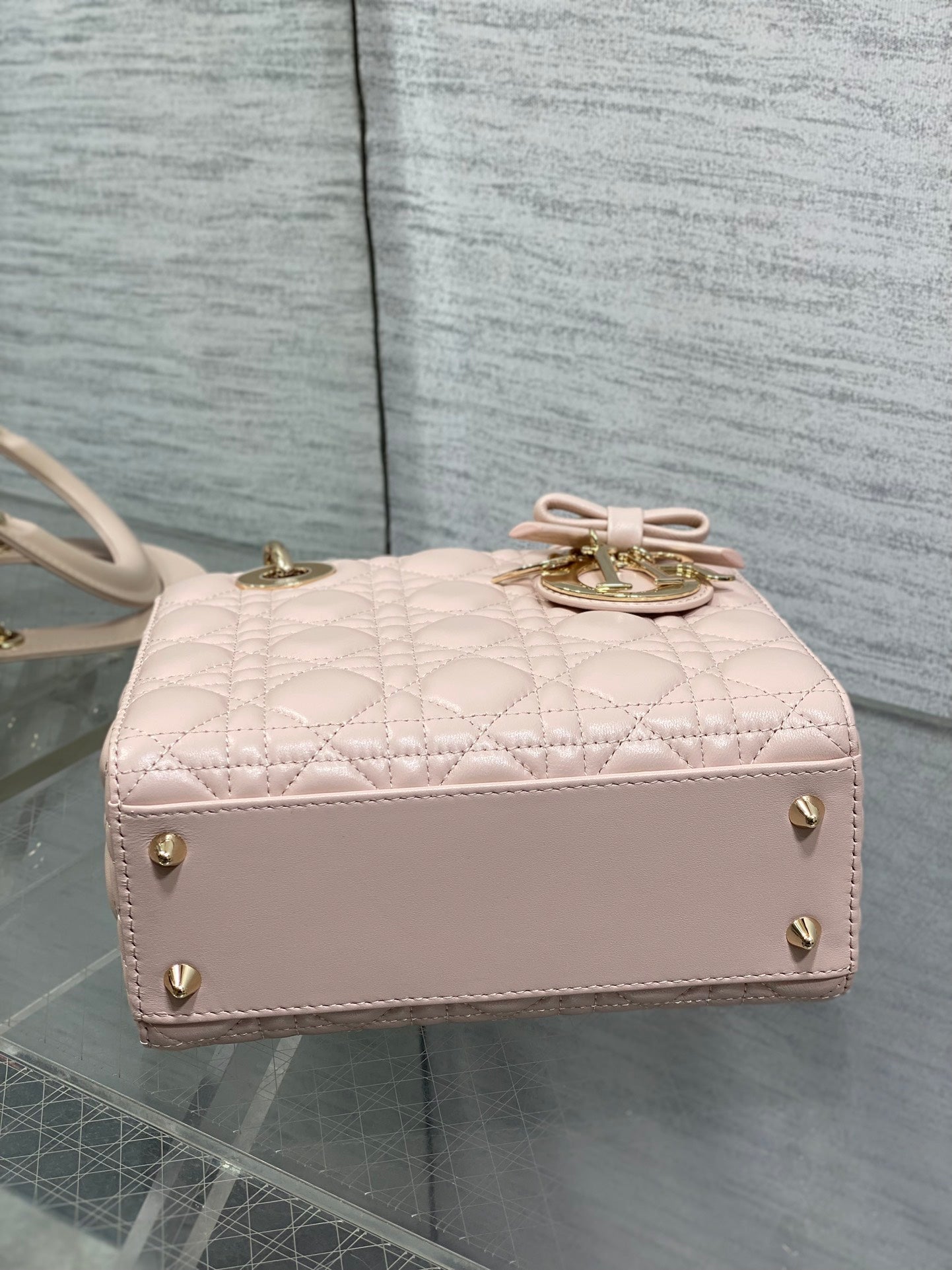 Light pink quilted handbag with top bow detail and gold-tone studs along the front