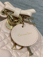 Light pink quilted handbag close-up with gold-tone hardware and "Christian Dior" charm