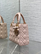 Light pink quilted mini handbag with top handles and gold-tone charm on the front