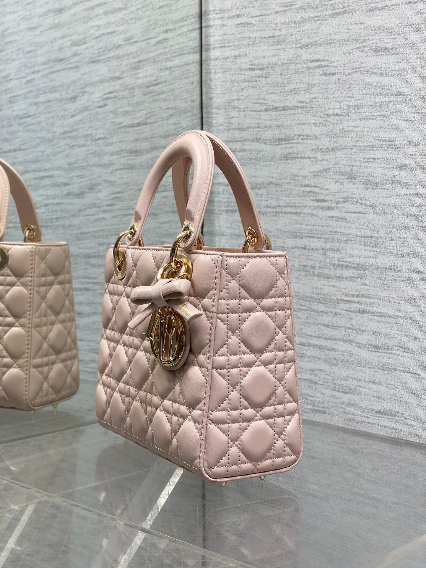 Light pink quilted mini handbag with top handles and gold-tone charm on the front