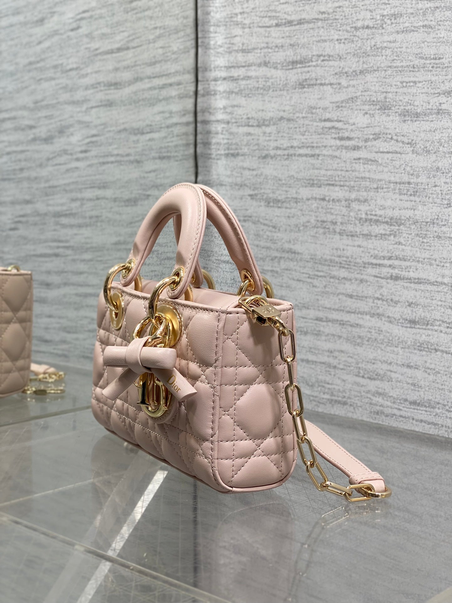 Dior bag side view in pale pink quilted leather with gold chain strap