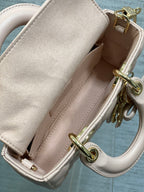Dior bag interior view with pale pink leather lining and gold hardware ring