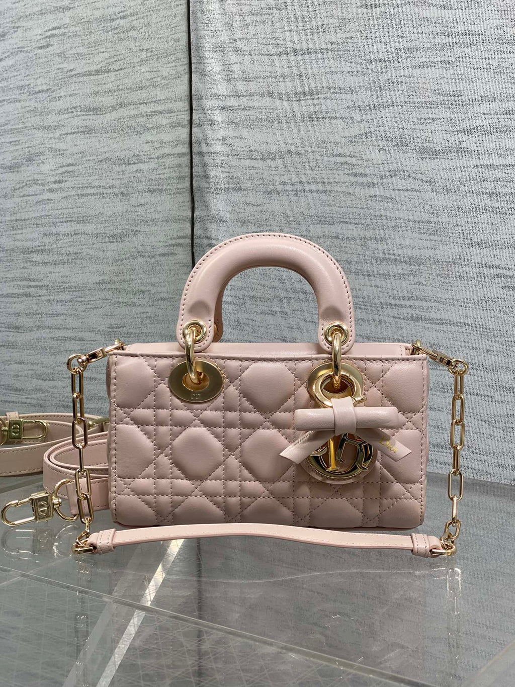 Dior bag in pale pink quilted leather with top handles, bow detail, and gold chain strap