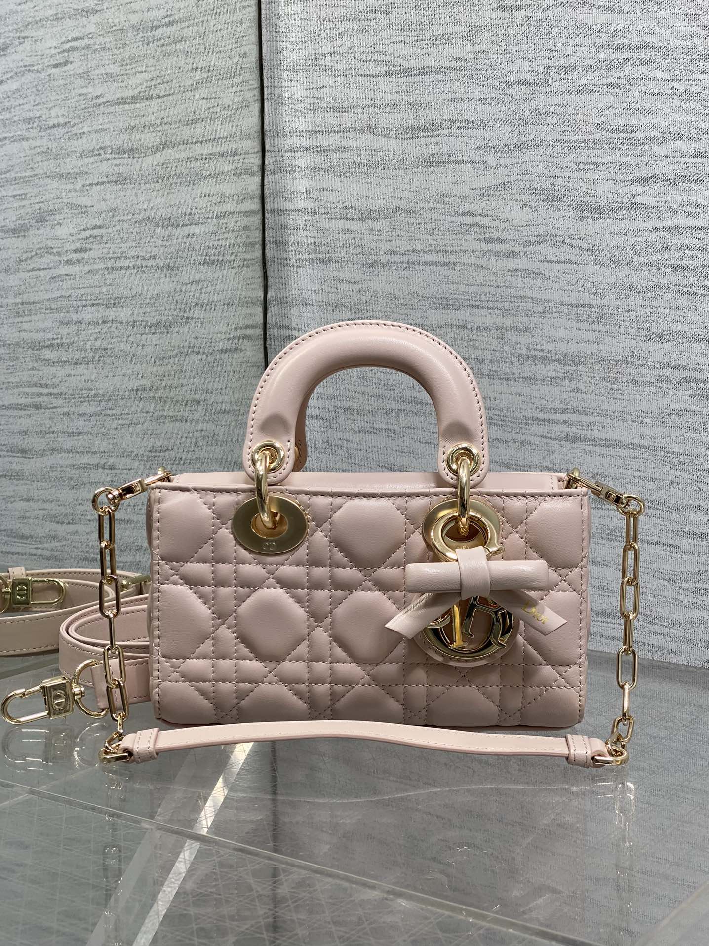 Dior bag in pale pink quilted leather with top handles, bow detail, and gold chain strap