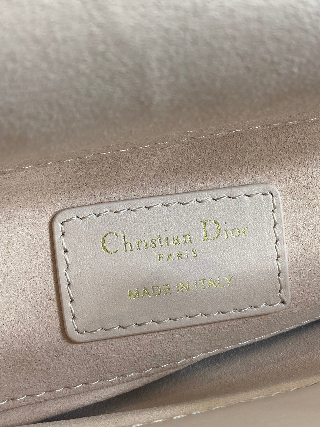 Dior bag label on pale pink leather reading “Christian Dior PARIS”