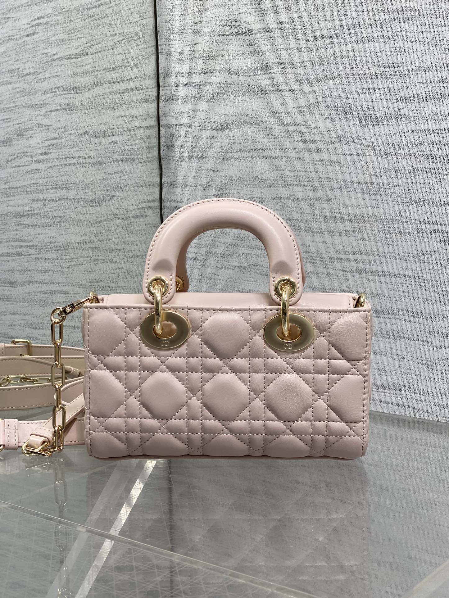 Dior bag in pale pink quilted leather with top handles, bow detail, and gold chain strap