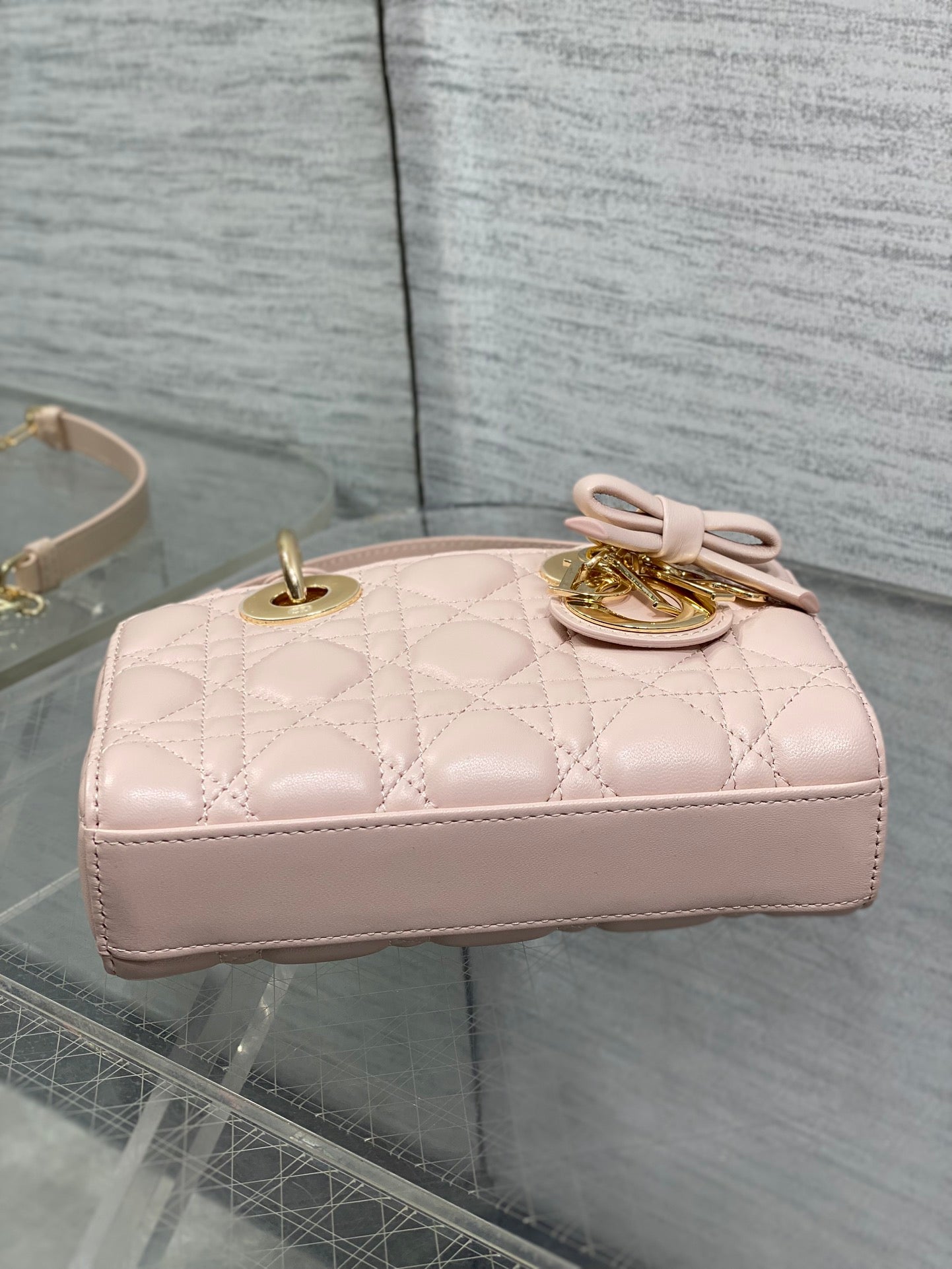 Dior bag back view in pale pink quilted leather with bow and top handle