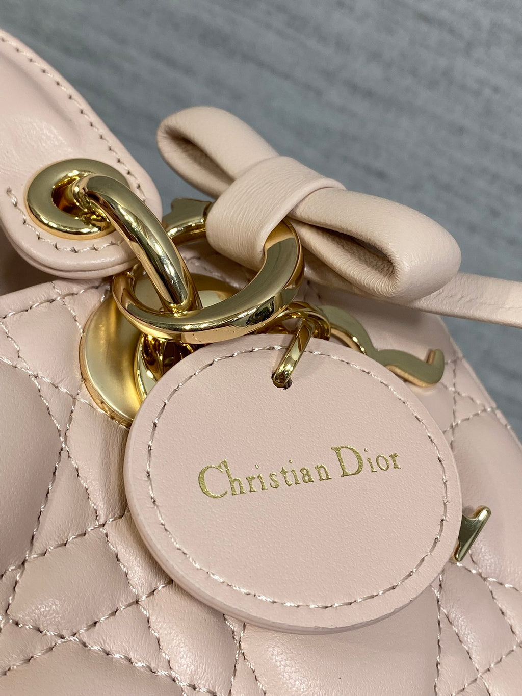 Dior bag round logo tag with “Christian Dior” on pale pink quilted leather