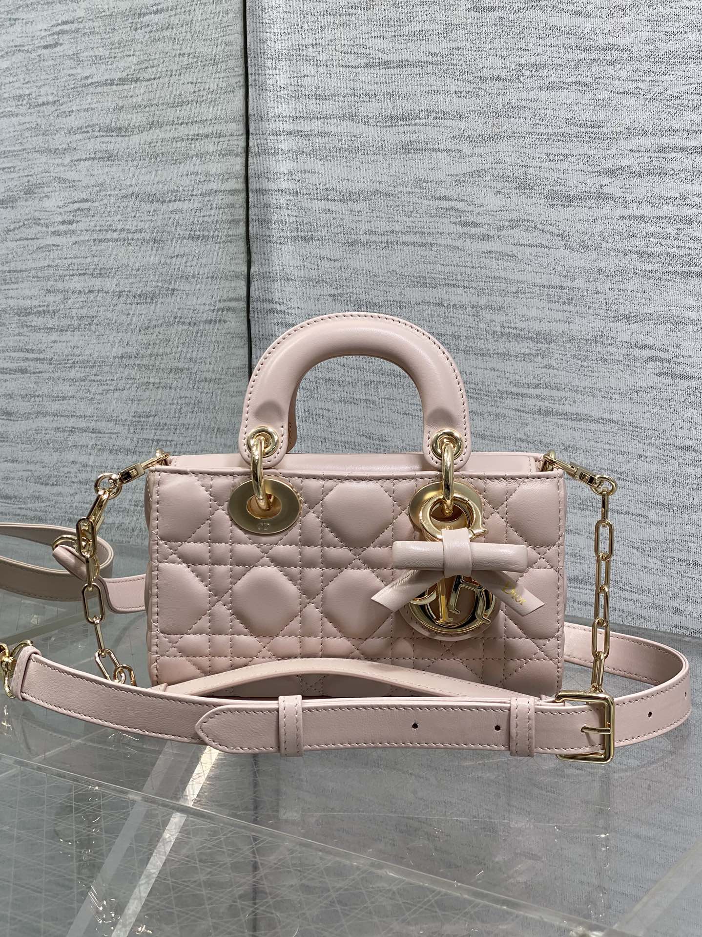 Dior bag in pale pink quilted leather with top handles, bow detail, and gold chain strap