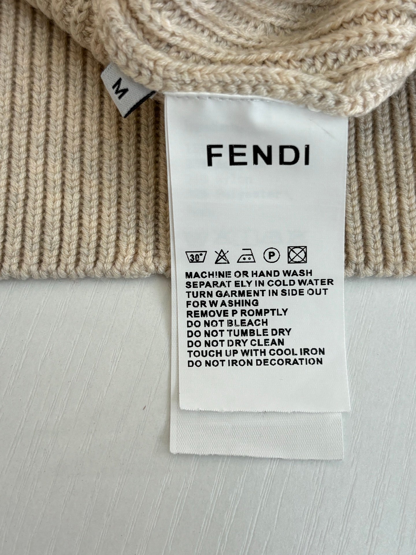 Fendi care label on cream knit sweater with washing instructions