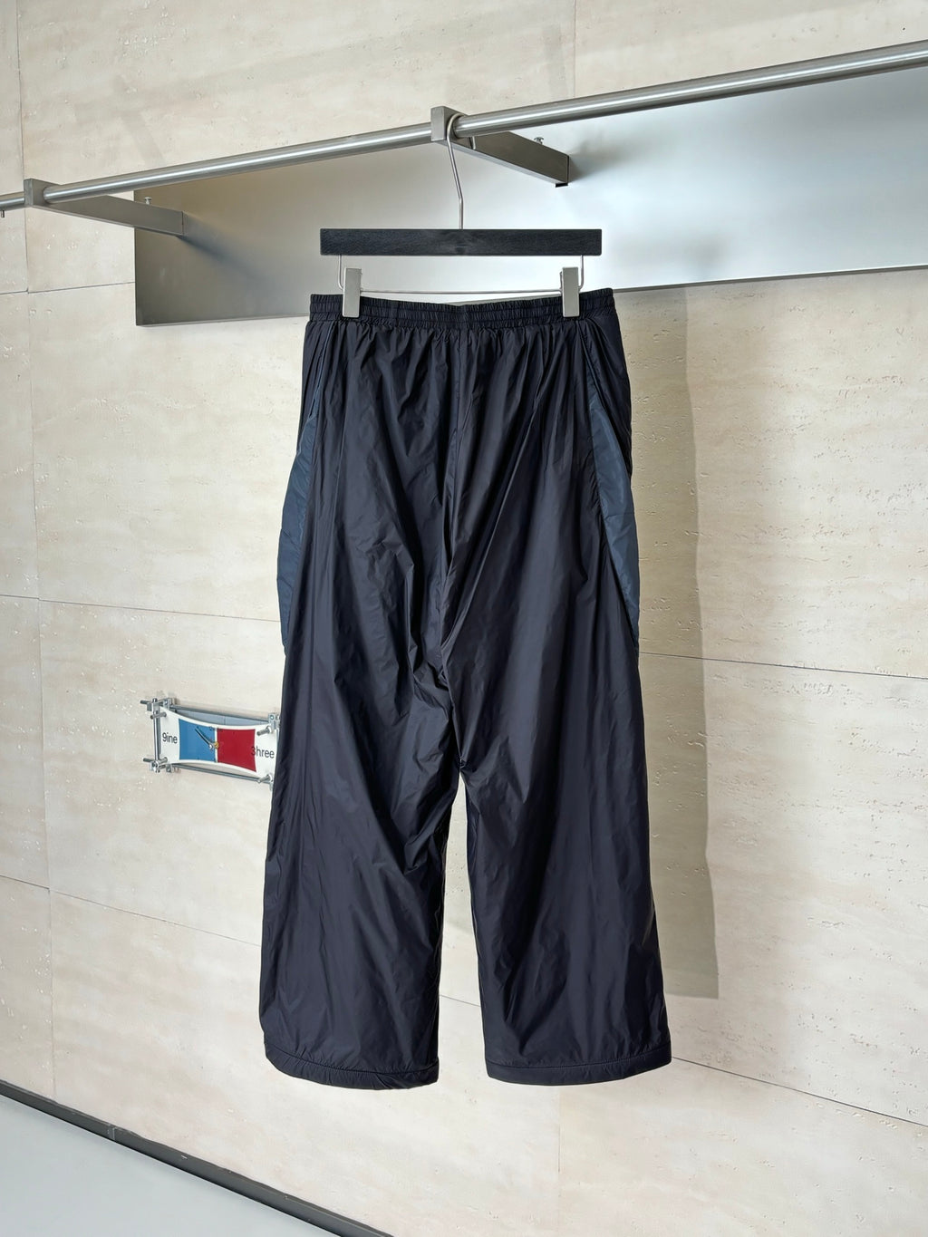 Balenciaga black wide-leg pants hanging on rack, elastic waistband and drawstring