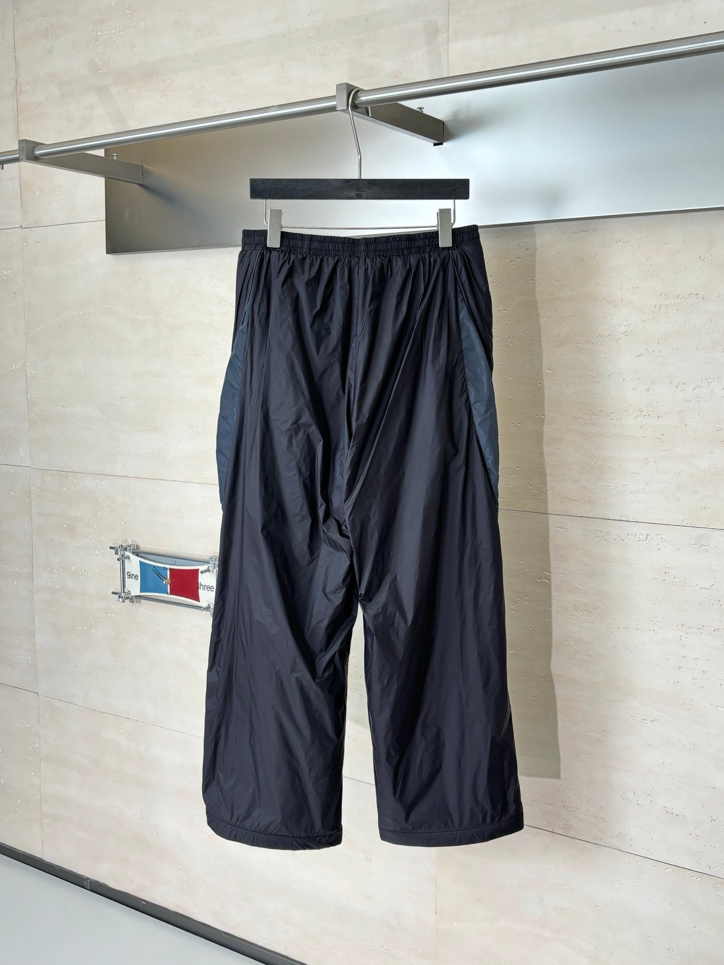 Balenciaga black wide-leg pants hanging on rack, elastic waistband and drawstring