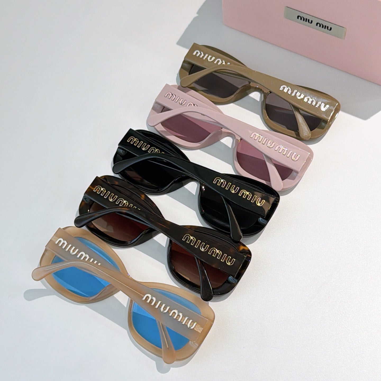 MiuMiu sunglasses assortment with mixed frames and tinted lenses, shown in a group.