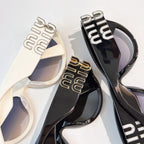 Pair of MiuMiu cat-eye sunglasses in cream and black with metal logo arms
