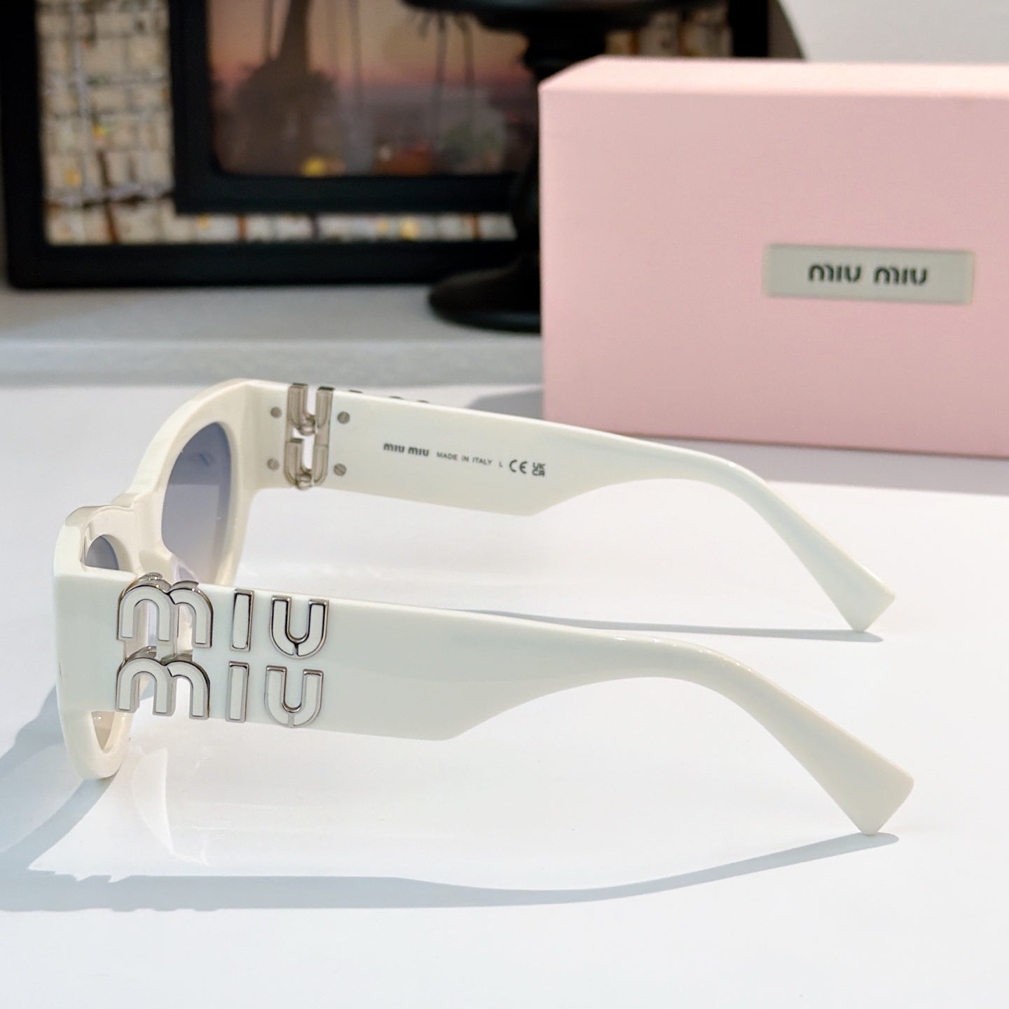 MiuMiu cat-eye sunglasses, white frame with metal logo detail at temple