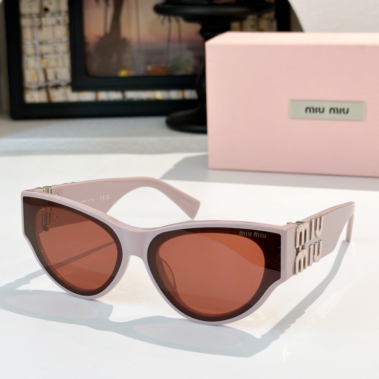 MiuMiu cat-eye sunglasses with pale pink frames and amber tinted lenses