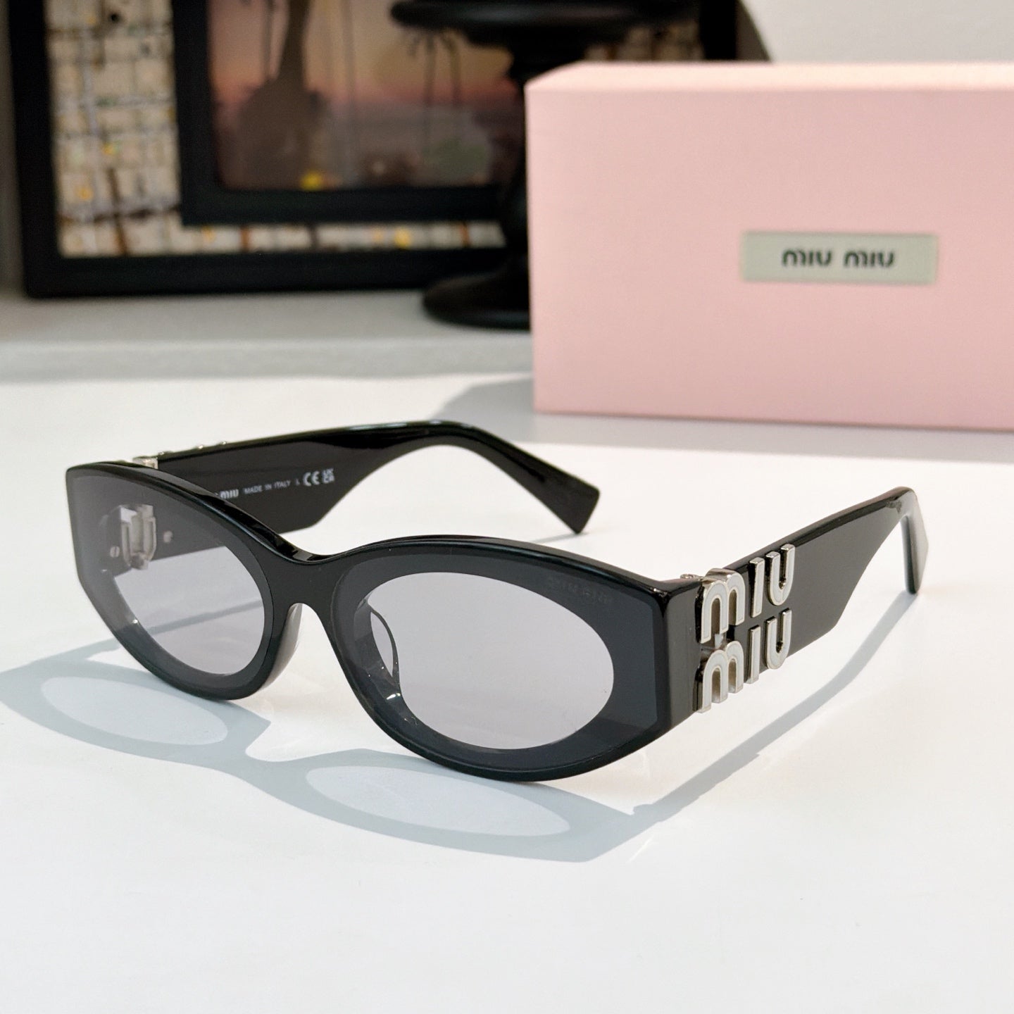 Black sunglasses with gray lenses and gold Miu Miu logo on the temples