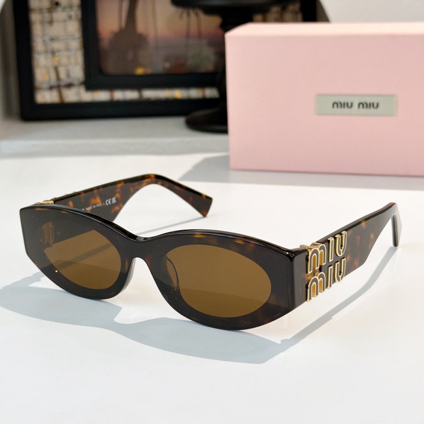Tortoiseshell sunglasses with amber-brown lenses and gold Miu Miu logo on the temples
