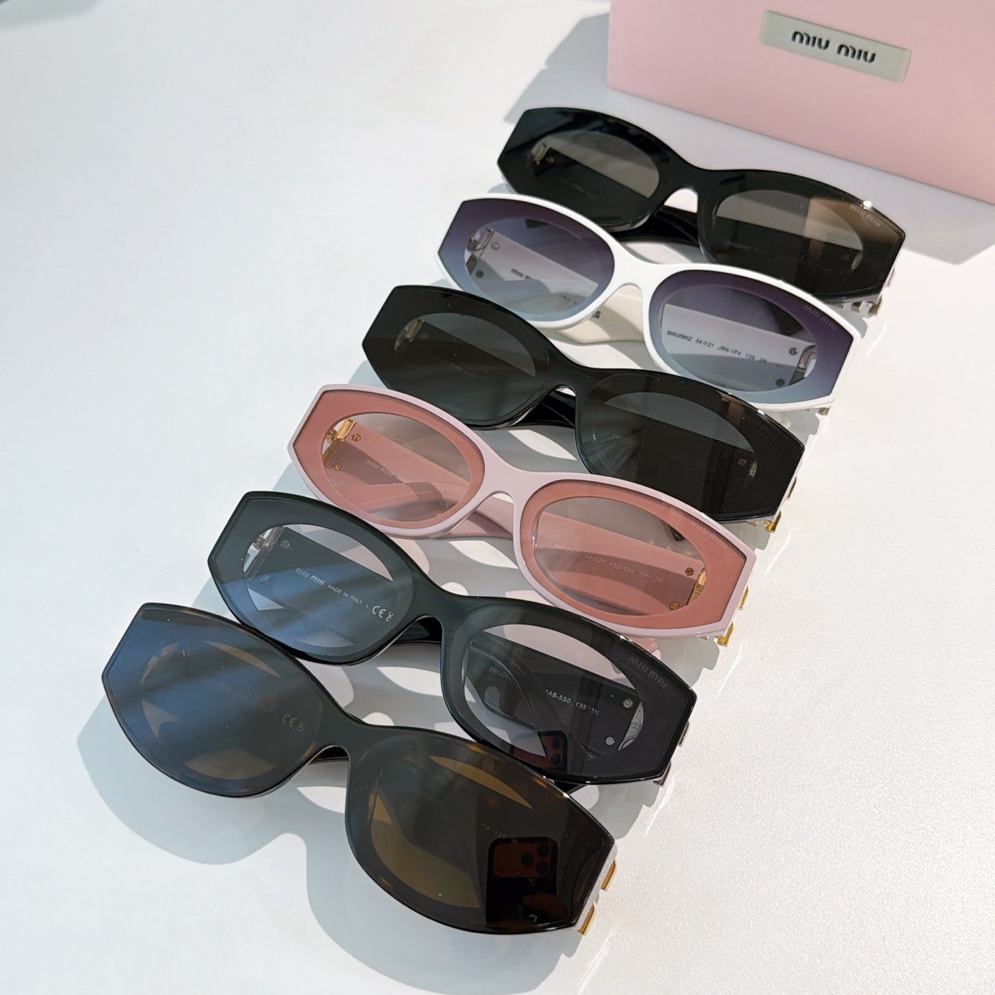 Assorted sunglasses with tinted lenses in black, white, blush, and dark frames