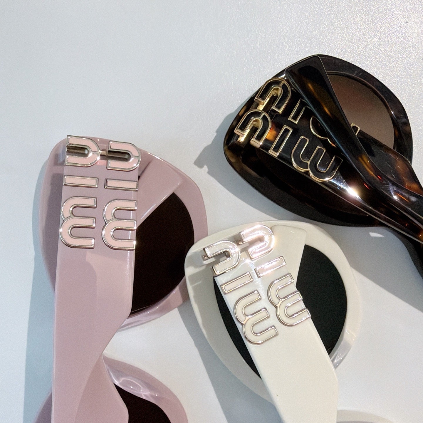 MiuMiu sunglasses logo arms close-up on pink and black frames