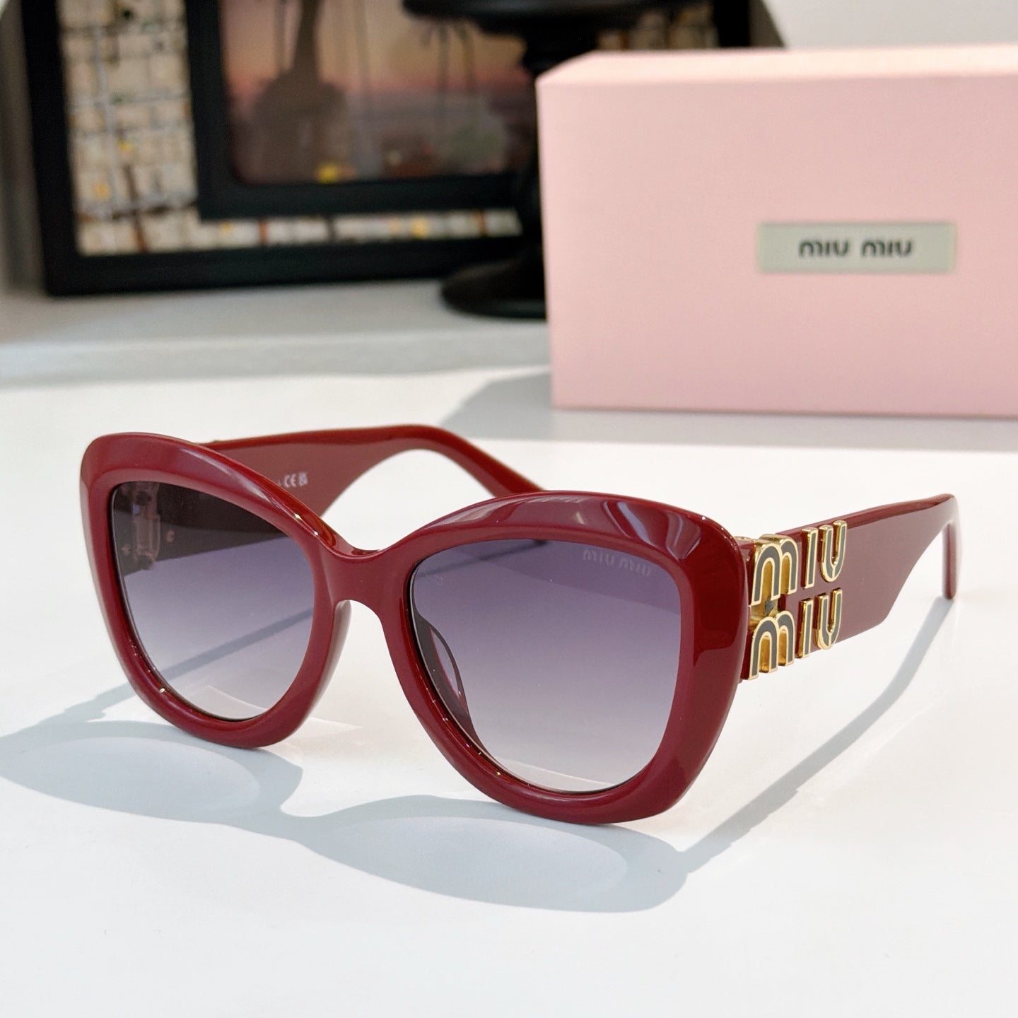 MiuMiu cat-eye sunglasses with red frames and purple tinted lenses, gold logo arms