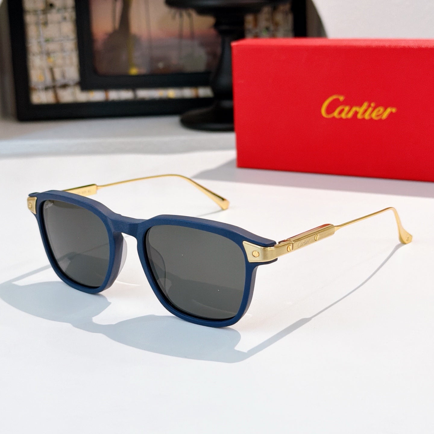 Sunglasses with blue frame and dark lenses, gold-tone accents on metal temples.