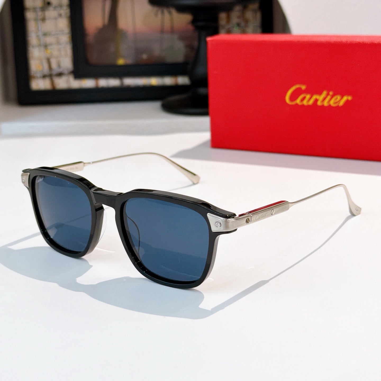 Sunglasses with gray frame and blue-tinted lenses, metal temples with subtle gold detail.