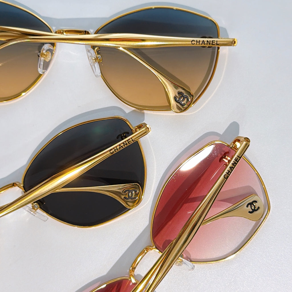 Assorted cat-eye sunglasses with gold frames and tinted lenses in dark and pink