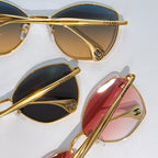 Assorted cat-eye sunglasses with gold frames and tinted lenses in dark and pink
