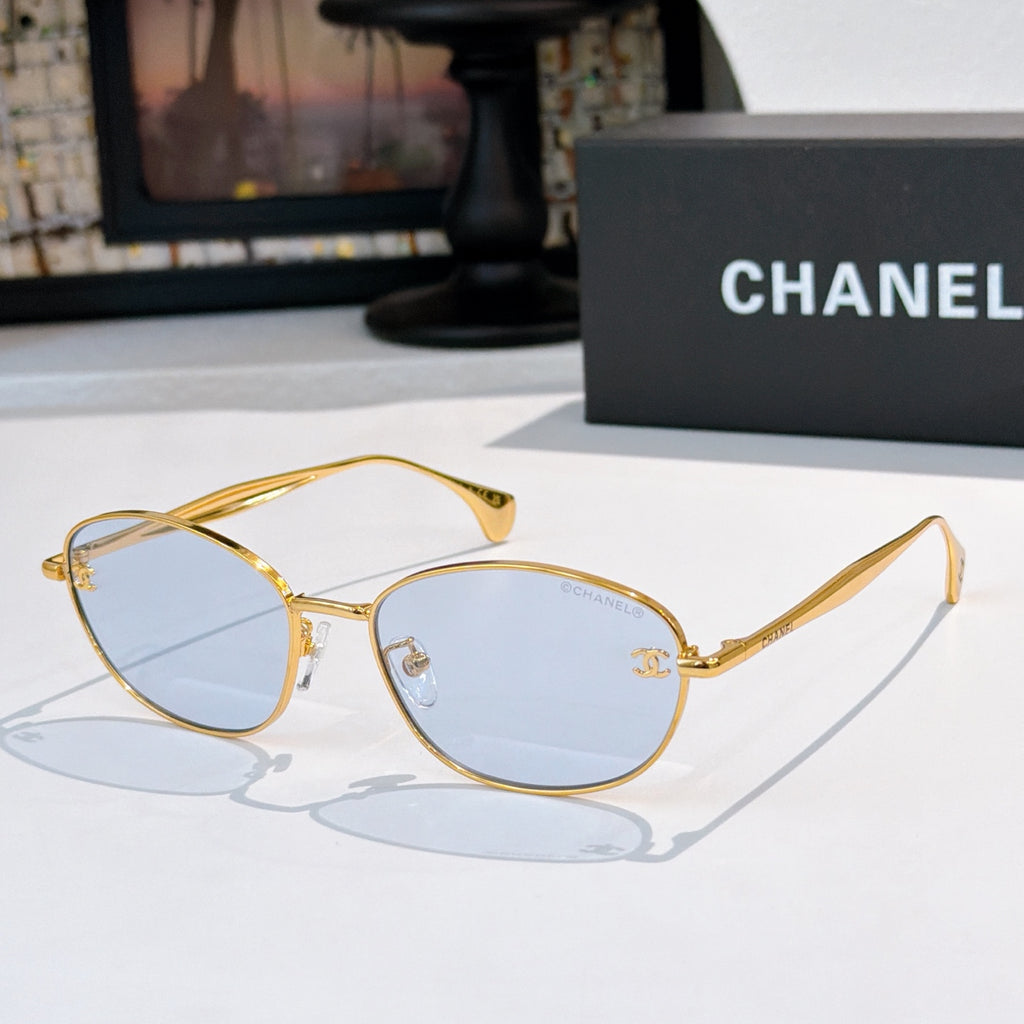 Sunglasses with gold-tone frame and light blue tinted lenses, oval shape