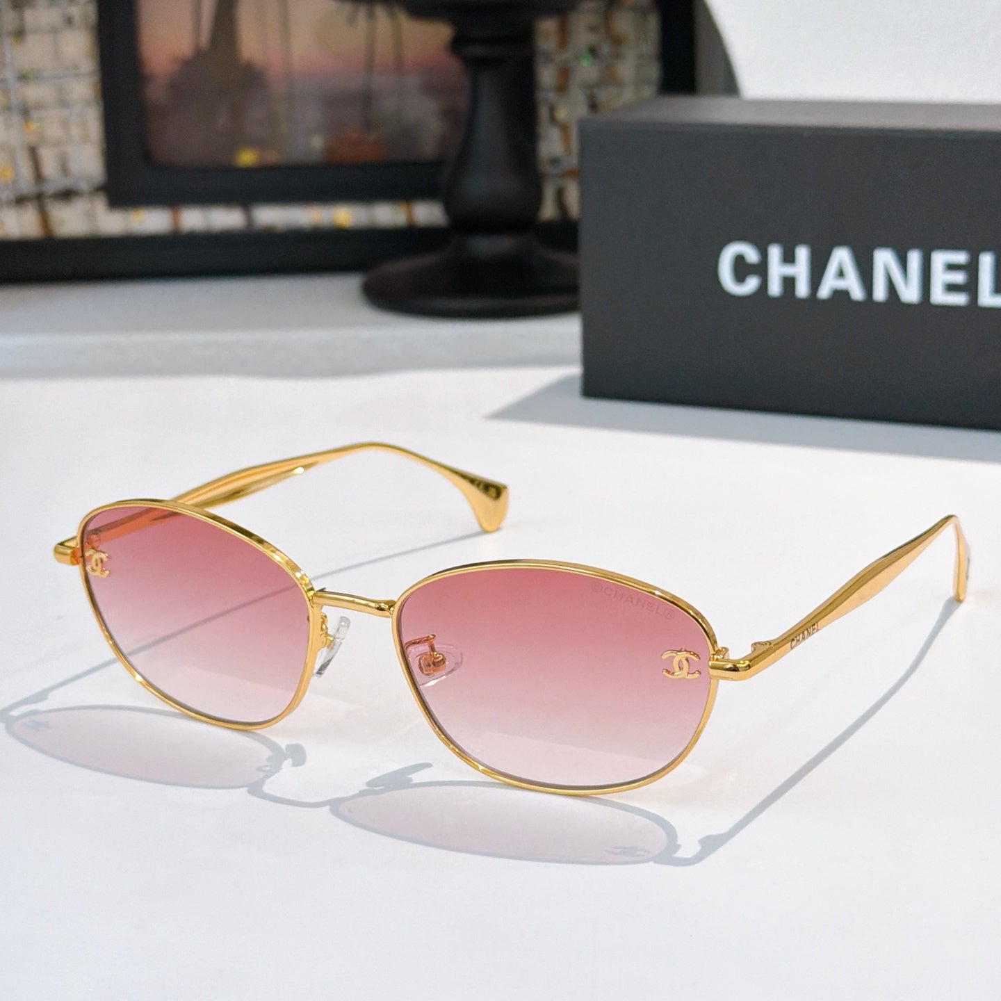 Sunglasses with gold-tone frame and pink tinted lenses, oval shape