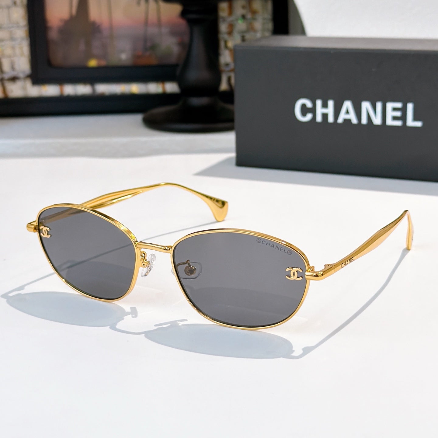 Sunglasses with gold-tone frame and dark gray tinted lenses, oval shape
